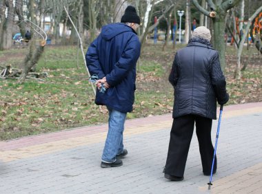 Yaşlı yaşlı adam ve bir sopa ile yürüyen kadın