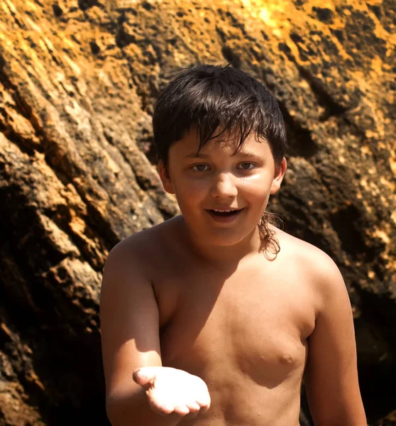 Garoto sorridente no fundo do mar e pedras — Fotografia de Stock