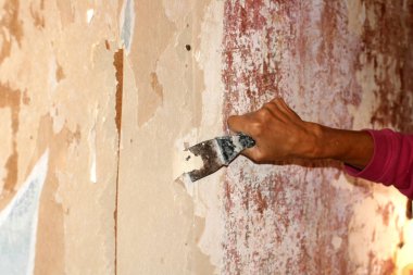 Duvarlar için duvar kağıdı bir spatula ile hazırlanıyor. Evde tamir.