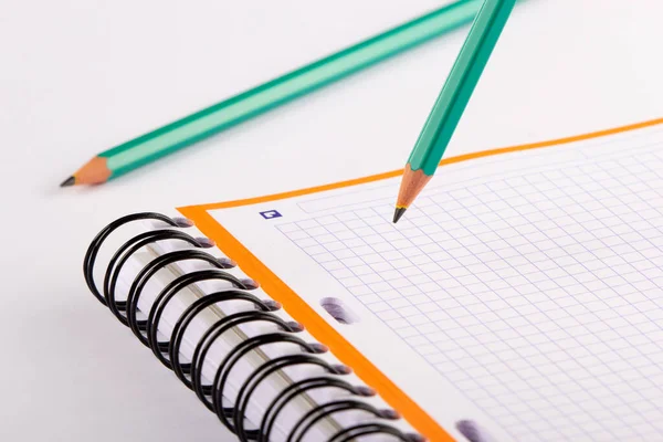 Green pencil writing in a checkered notebook. A card with an orange frame.