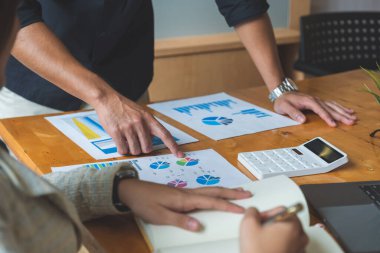 Finansal tablolara işaret ederek kadın ve erkeğin ellerinin tartıştığı yakın çekim