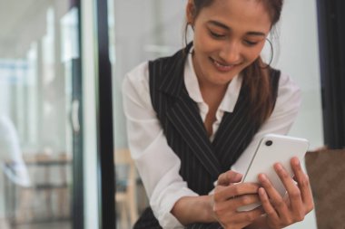 Akıllı telefon kullanırken gülümseyen profesyonel mutlu kadın görüntüsü.
