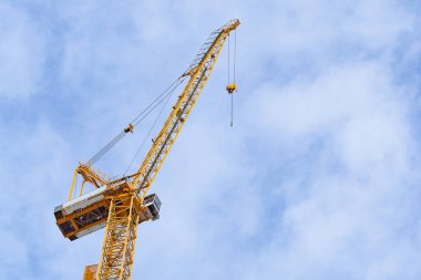 Gökyüzü arka planında vinçleri olan bir inşaat alanı. Mavi gökyüzü arka planında ağır kaldırmak için inşaat endüstrisinin büyük sarı makine inşaat vinç aracı. İş mühendisliği ekipmanları modern