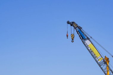 Gökyüzü arka planında vinçleri olan bir inşaat alanı. Mavi gökyüzü arka planında ağır kaldırmak için inşaat endüstrisinin büyük mavi makine inşaat vinç aracı. İş mühendisliği ekipmanları modern etkinlik