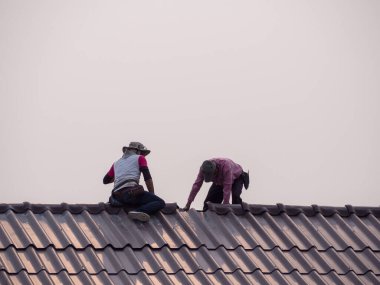 Çatıda tamirat yapan adamların arka görüntüsü. Metin için boşluk