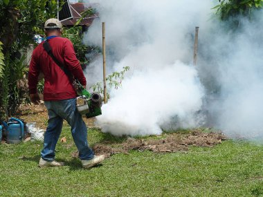 Man are working fogging to eliminate mosquitoes. In the rain season  be careful of mosquitoes and protect dengue fever spread clipart