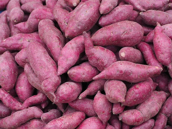 Piyasada satılık taze mor yer elması yığını. Meyve sağlığı kavramı