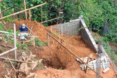 Ev inşa etmek için eğimli bir alanda çukur kazan işçiler. Metin için boşluk