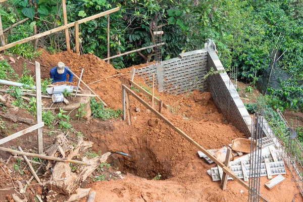 Ev inşa etmek için eğimli bir alanda çukur kazan işçiler. Metin için boşluk