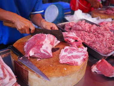 Kasap elleri taze pazar için domuz etini parçalara ayırıyor.