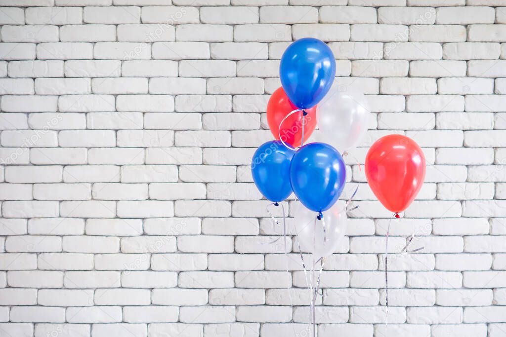 Bright balloons red, blue and white put together on the right hand side near white brick wall in the background. Copyspace for text. 4th of July, Independence day, Memorial day. Celebration time