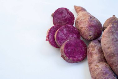 Dilimlenmiş taze mor tatlı patateslerin yakın plan çekimi ve beyaz arka plan. Metin için boşluk