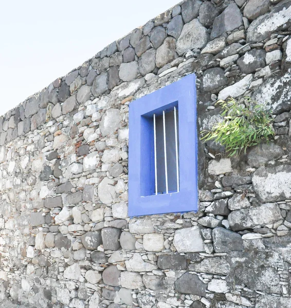Blue window and stone house on the wall