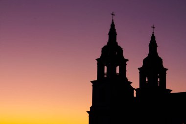 Gün batımında bir Ortodoks katedralinin iki kulesinin siyah silueti.