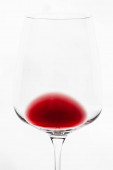 Vízszintes közeli kép egy izolált tálról és egy rész átlátszó borosüveg borról, benne némi vörösborral a fehér háttérben