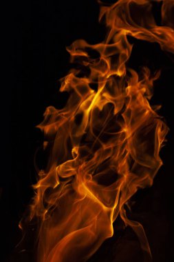 İzole edilmiş parlak turuncu bir alevin dikey görüntüsü. Siyah arka planda sayısız dil var. 