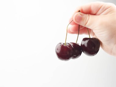 Bir çocuğun eli üç kiraz tutar.