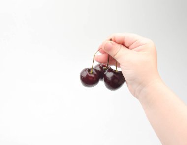 Bir çocuğun eli üç kiraz tutar.