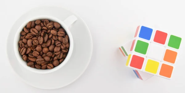 Kahveli beyaz bardak ve beyaz arka planda rubik küp.