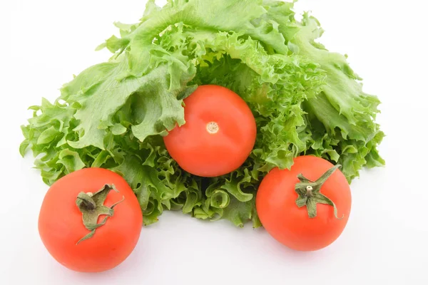Beyaz tabakta yeşil salata ve üç domates.