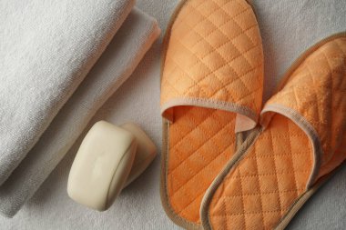 Otelde duş seti iki beyaz havlu, yumuşak şeftali rengi terlikler ve beyaz bir paspasın üzerinde iki parça kokulu sabun.