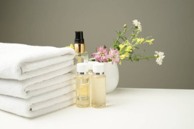Masaj için komodine kurulmuş temiz beyaz havlu, şişelerde çeşitli masaj yağları ve güzel bir demet çiçek.
