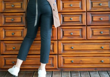 Önlüklü, kot pantolonlu ve beyaz spor ayakkabılı bir garson elinde bir postal ile kamuflajın önünde duruyor ve müşteriye fatura hazırlıyor.