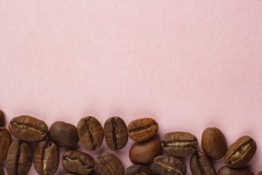 Kahve çekirdekleri pembe arka planda.