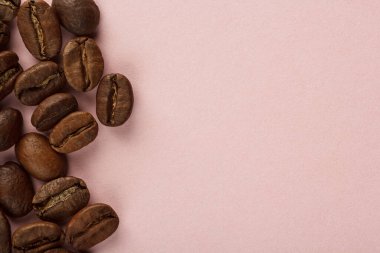 Kahve çekirdekleri pembe arka planda.