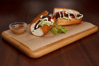 Pirzolalı sandviç, kraft kağıdıyla kaplı bir emziğin üzerinde ve sosun yanında.