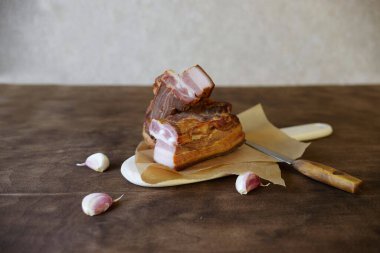 Tahta arka planda sarımsaklı domuz pastırması dilimi.