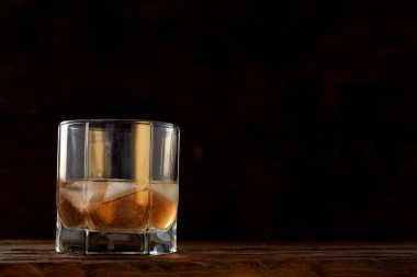 Buzlu viski alayım. Koyu arkaplanda, ahşap masanın üzerindeki cam bir depoda soğuk alkollü içecek. Bir bardak romlu alkolü yakından çek. Konyak yakın plan, içki, kokteyl.