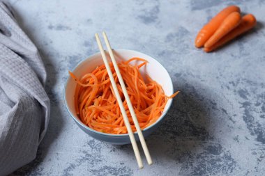 Taze ve sağlıklı sebzeler Kore salatası beyaz tabakta rendelenmiş havuç. Sağlıklı beslenme ve vejetaryen gıda konsepti. Sebzeler ve aşçılık geçmişi. Üst Manzara. Organik baharatlı havuç salatası..