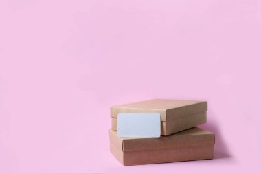 Pembe arka plan manzaralı karton el işi bir kutu. Teslimat konsepti, posta, varış yerleri, karantina süresi konuyla ilgili. Uzayı kopyala Metin için yeri olan bir kartvizit..