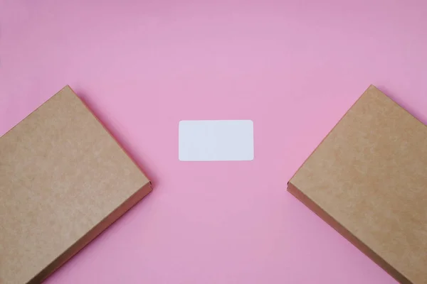 Delivery business card with place for text. Cardboard craft box with cover on pink background top view. The concept of delivery, mail, destinations, the quarantine period is relevant. Copy space.