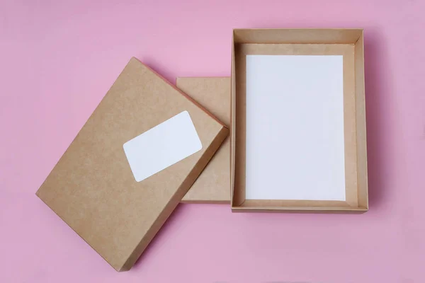 open Cardboard craft box with cover on pink background top view. The concept of delivery, mail, destinations, the quarantine period is relevant. Copy space. Delivery business card with place for text.