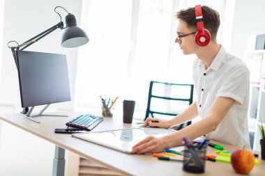 Bir genç adam gözlük ve kulaklık bilgisayar çalışıyor. Adam bir manyetik kurulu ve işaretleri olmadan.