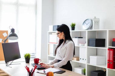 Genç bir kız masanın ayakta ve metin klavyede yazarak. Belgeler ve bir işaretleyici kızın yanında yalan.