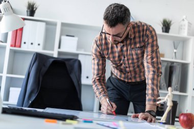 Bir adam ofiste masanın yanında duruyor ve bir işaretleyici manyetik tahtaya çizer.