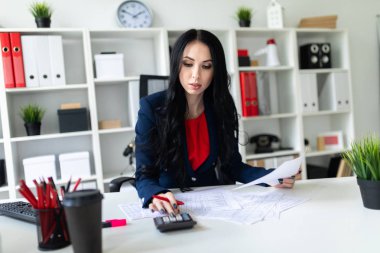 Hesap makinesi ve Office belgeleri ile masada çalışan güzel bir genç kız