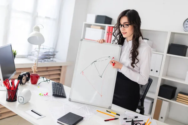 Güzel bir genç kız bir Ofis Masası standları ve manyetik bir işaretleyici manyetik tahtaya çizer.