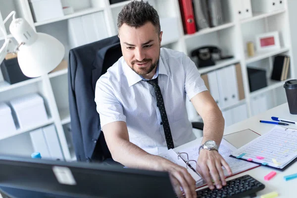 一个男人坐在办公室的桌子旁, 用文件和电脑工作。. — 图库照片