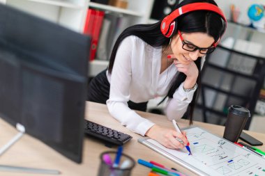 Genç bir kız kulaklık tablo anlamına gelir ve bir işaretleyici manyetik bir tahtaya çizer.