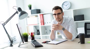 Ofiste bir tabloda yakınındaki bir genç adam gözlük standları.