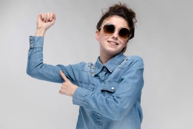 Siyah gözlüklü genç esmer kız. Kedi gözlük. Saç bir topuz toplanır. Kız puan bir parmak kas.