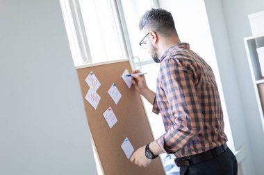 Bir adam ofis pencerenin yanında duruyor ve bir işaretleyici çıkartmaları yazıyor.