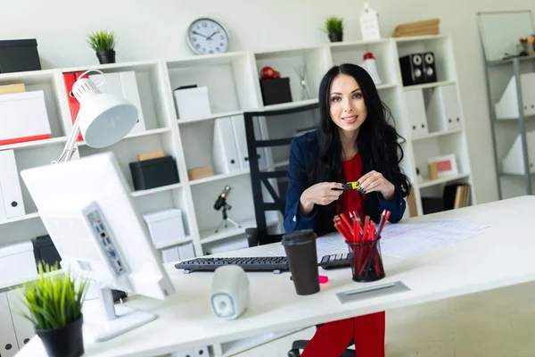 Krásná mladá dívka sedí v kanceláři na stole a drží v ruce žlutou značku. — Stock fotografie