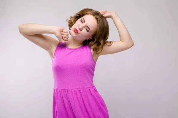 Charmante junge Mädchen in rosa Kleid auf grauem Hintergrund. ein junges Mädchen, das sich hochzieht — Stockfoto