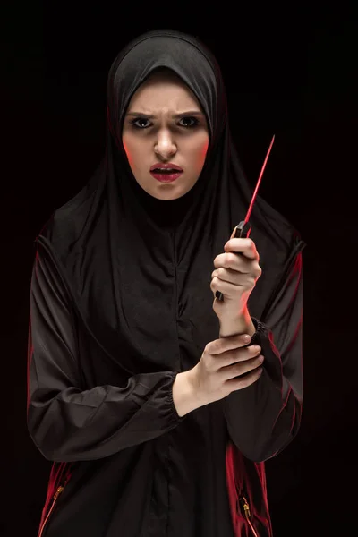 Porträt der schönen verzweifelten verängstigten jungen Muslimin mit schwarzem Hijab und Messer in der Hand als Schutzkonzept auf schwarzem Hintergrund — Stockfoto
