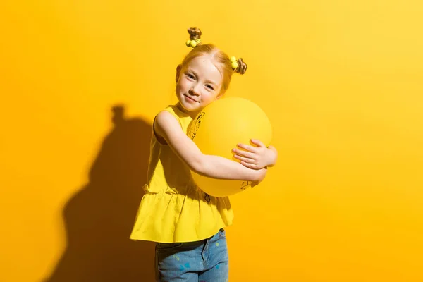 Dívka s červenými vlasy na žlutém podkladu. Dívka je objímání žlutá bublina. — Stock fotografie